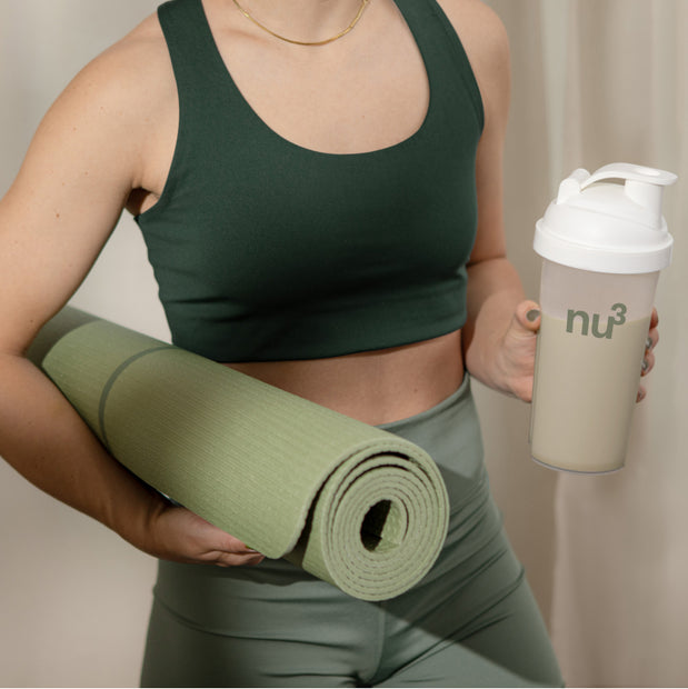 Sportliche Frau mit Shake und Yogamatte